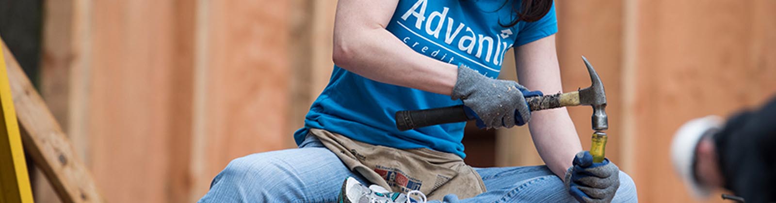 Advantis volunteer using a hammer while volunteering at Habitat for Humanity