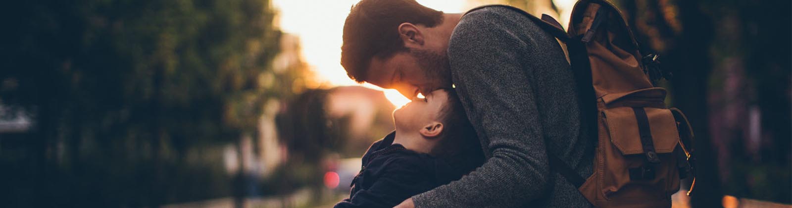 man kissing his son's forehead while outdoors