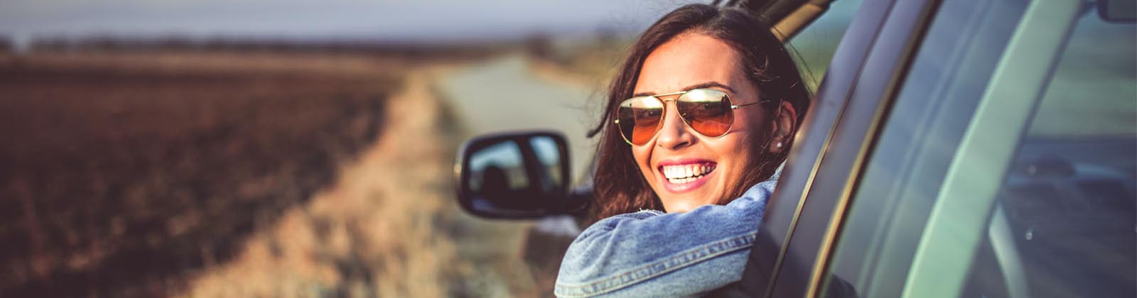 woman looking out her car window smiling