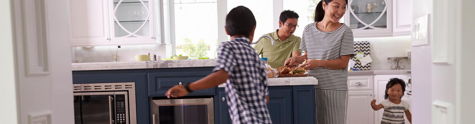 family in a kitchen smiling while two young children play