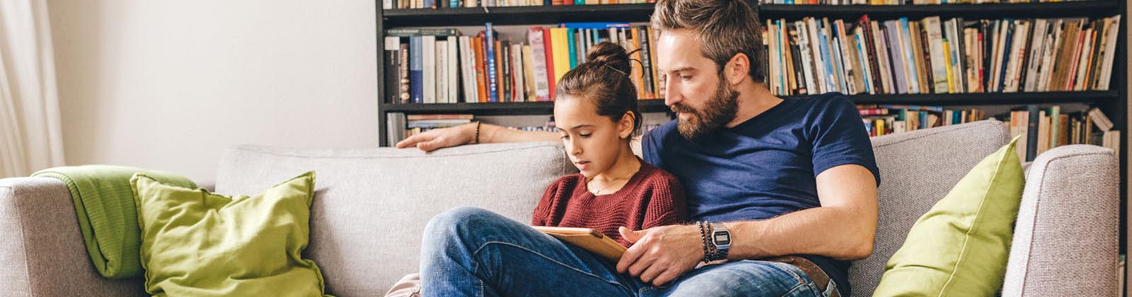 father and daughter reading on a couch together