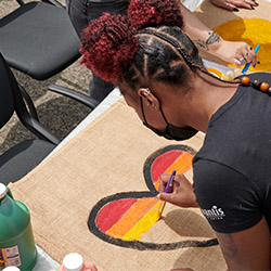 Advantis team member painting a rainbow heart on a sign during a LGBTQ+ Pride volunteer event.